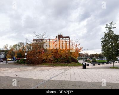 Salford, Vereinigtes Königreich - 8. November 2025: Herbstfarben umrahmen eine Salford plaza mit einem Backsteingebäude und bewölktem Himmel. Stockfoto