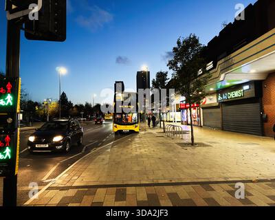 Salford, Großbritannien - 8. November 2025: Abendliches Stadtleben in Salford mit Bus, Autos und Fußgängern in der Nähe von Geschäften. Stockfoto