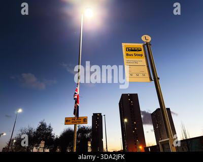 Salford, Großbritannien - 08. November 2025: Abendlicher Blick auf ein Schild mit Bushaltestelle in Salford, Großbritannien, mit Ampeln und Skyline. Stockfoto