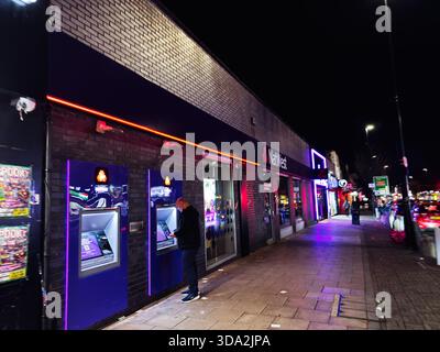 Salford, Großbritannien - 8. November 2025: Ein Mann, der nachts in Salford einen blauen Geldautomaten benutzt. Stockfoto