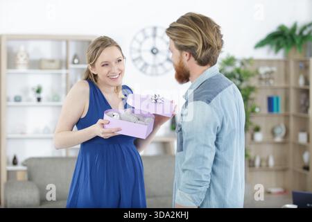 Glücklicher, fröhlicher Ehemann, der seiner Schwangeren einen Schenker gab Stockfoto