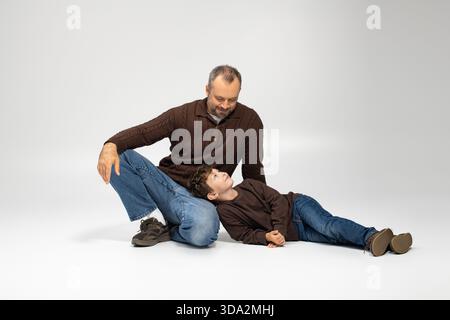 Vater und Sohn teilen einen Moment von Herzen, während sie gemeinsam in einem fröhlichen Spiel zuhause spielen. Stockfoto