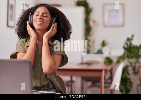 Happy Woman Genießt Musik Mit Kopfhörern In Gemütlicher Atmosphäre Im Home Office Stockfoto