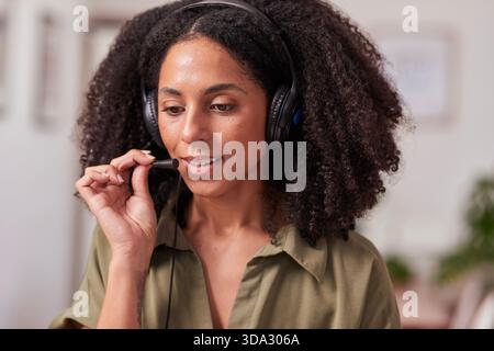 Professionelle Frau Mit Headset-Mikrofon Im Home Office, Konzentriert Und Freundlich Für Callcenter Oder Remote-Arbeiten Stockfoto