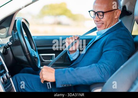 Glücklicher Geschäftsmann In Blauem Anzug Schnallt Den Sicherheitsgurt Im Auto, Fahrbereit Stockfoto
