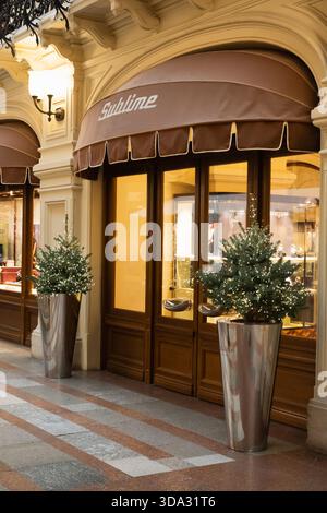 Russland. Moskau. Dezember 2025. Luxuriöses ZAHNFLEISCHGESCHÄFT. Weihnachtlich dekorierte Ladenfront mit beleuchtetem Eingang und Tannen in Pflanzgefäßen im Luxusgeschäft Stockfoto