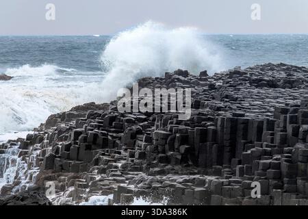 Basaltsäulen, die durch den Ausbruch von alten vulkanischen Spalten entlang der Küste des Giant's Causeway in der Nähe von Bushmills, Nordirland, mit heftiger Welle verursacht wurden Stockfoto