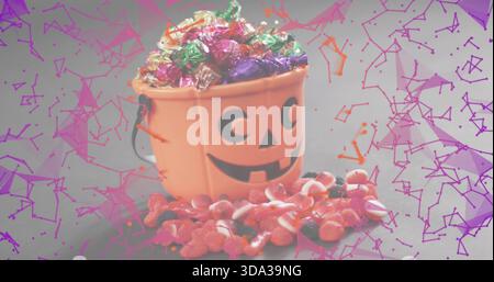 Mit orangefarbenem Jack-o'-Laterne-Eimer mit Bonbons auf grauem Tisch verschüttete Gummiüberlagerung in Magenta Stockfoto