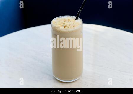 Hohes Glas Eislatte mit Mandelflocken. Nahaufnahme einer Vanille- oder Nussfrappe in einem klaren Glas Stockfoto