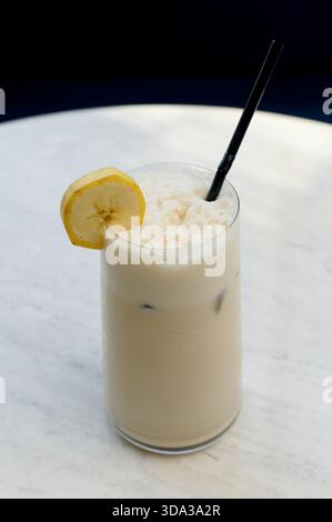 Hohes Glas Eislatte mit Mandelflocken. Nahaufnahme einer Vanille- oder Nussfrappe in einem klaren Glas Stockfoto