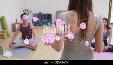 Leitender Lehrer trägt einen grauen BH, Leggings, die die Schüler auf Matten im Yoga-Studio führen, rosa Überzug Stockfoto