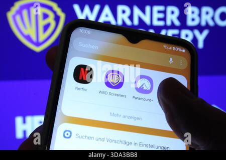 Auf einem Laptop wurde die Website vom Hollywood-Konzern Warner Bros. Discovery aufgerufen. Davor sind auf einem Smartphone die Apps der Paramount Pictures Corporation von Netflix und Warner Bros. Discovery zu sehen. Netflix und Paramount wollen Warner Bros. Discovery übernehmen. Symbolbild/Symbolfoto. Schnelsen Hamburg *** die Website der Hollywood-Gruppe Warner Bros Discovery wurde auf einem Laptop davor aufgerufen, die Apps der Paramount Pictures Corporation von Netflix und Warner Bros Discovery sind auf einem Smartphone zu sehen Netflix und Paramount will Warner Bros Discovery Sym übernehmen Stockfoto
