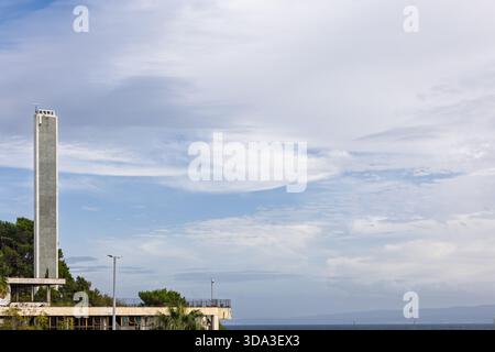 Städtisches Stadtbild mit einem hohen, modernen Betongebäude, umgeben von klarem Himmel und Palmen, das eine harmonische Mischung aus Natur und Moderne bietet. A Stockfoto