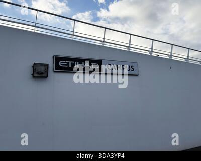 Manchester, Großbritannien - 16. November 2025: Schild auf dem Etihad Campus an der weißen Wand vor dem Manchester Stadion, blauer Himmel und Geländer darüber. Stockfoto