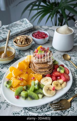 Köstlicher Stapel glutenfreier Pfannkuchen, serviert mit frischem Obstsalat. Stockfoto