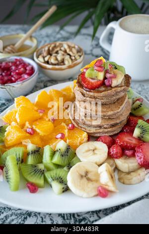 Köstlicher Stapel glutenfreier Pfannkuchen, serviert mit frischem Obstsalat. Stockfoto