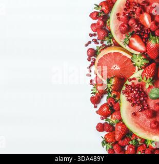 Rote Früchte und Beeren auf weißem Hintergrund. Wassermelone, Grapefruit, Erdbeeren, Himbeeren und Granatapfelsamen. Gesunder Sommer-Snack. Rahmen. Oben Stockfoto