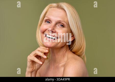 Wunderschöne, reife Frau mittleren Alters mit glühender Haut isoliert auf Oliven. Großaufnahme der Reifen alten Frau. Gesunde Gesichtshaut, Hautpflege mittleren Alters Stockfoto