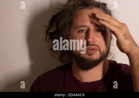 Der Mann fühlt Schmerzen und Stress und hält die Hand auf der Stirn Stockfoto