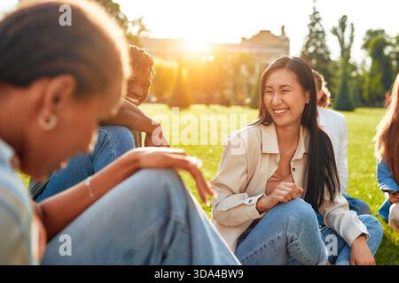 Auf einem sonnigen Campus versammelt sich eine Gruppe von Studenten, die sich an Diskussionen, Lachen und gemeinsamen Studien beteiligen, um einen Hauch von Freude zu schaffen Stockfoto