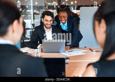 Erfolgreiche junge Menschen, die in einem Coworking-Raum arbeiten. Afroamerikanerin mit ihrem Team, das mit Laptop arbeitet, diskutiert Strategie und Geschäftsplan I Stockfoto