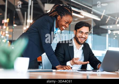 Erfolgreiche junge Menschen, die in einem Coworking-Raum arbeiten. Afroamerikanerin mit ihrem Team, das mit Laptop arbeitet, diskutiert Strategie und Geschäftsplan I Stockfoto