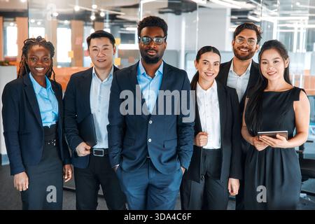 Team erfolgreicher junger Geschäftsleute in formellen Anzügen mit Laptops im modernen Büro. Junge Menschen unterschiedlicher Nationalitäten, die in einem Coworkin arbeiten Stockfoto
