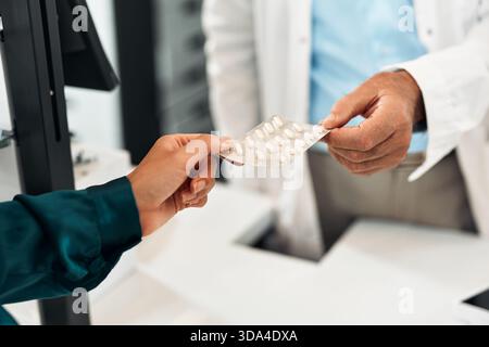 Nahaufnahme eines Apothekers, der einer Kundin am Tresen eine Blisterpackung mit weißen Pillen gibt. Konzentrieren Sie sich auf die Hände. Konzept: Pharmazie, Medizin, Gesundheit Stockfoto