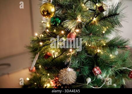 Künstlicher weihnachtsbaum, der den Innenraum mit funkelnden Lichtern und festlichen Ornamenten dekoriert Stockfoto