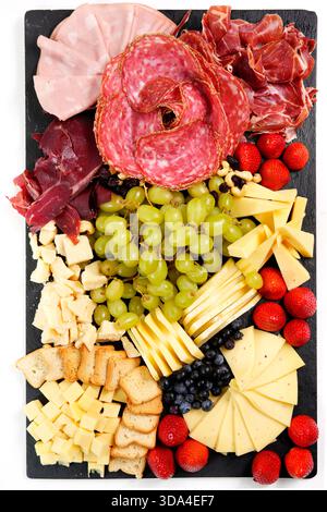 Gourmet-Wurstplatte mit einer Auswahl an Fleisch, Käse, Trauben, Erdbeeren und Toast als Vorspeise Stockfoto