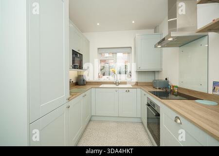 Moderne Küche mit Lichtschränken und einfachem Layout in einem Wohnhaus bei Tageslicht Stockfoto