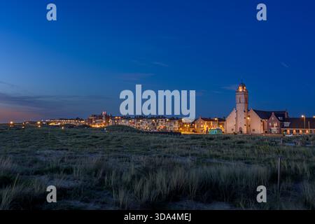 Katwijk aan Zee, Niederlande - 11. Juni 2022: Sonnenuntergang mit der blauen Stunde in Katwijk aan Zee von den Dünen bis zum Boulevard mit dem Andreaskerk. Stockfoto