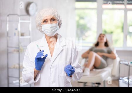 Porträt eines älteren Arztes mit Spritze. Stockfoto