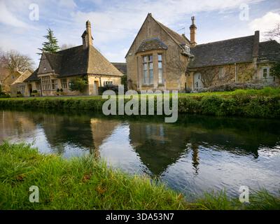 Historisches Stone Schoolhouse am Fluss – Cotswolds Village Reflection England Großbritannien Stockfoto