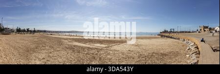 Panoramablick auf einen breiten Sandstrand neben dem Meer unter klarem Himmel Stockfoto