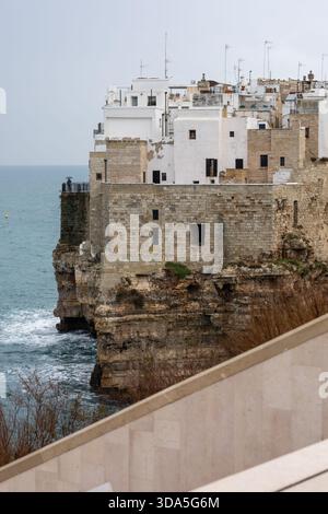 Alte weiß getünchte Gebäude thronten prekär auf einer steilen Kalksteinklippe mit Blick auf die adria in polignano a Mare, apulien, italien, unter einem Ov Stockfoto