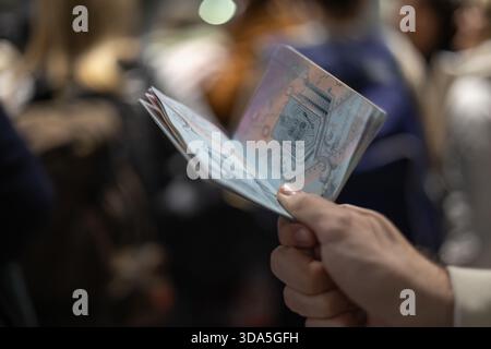 Eine Nahaufnahme der Hand einer Person mit Reisepass, die auf den Innenseiten des Nationalwappens geöffnet ist, möglicherweise während der Warteschlange oder Stockfoto