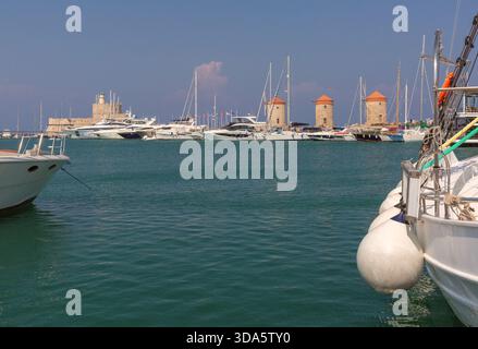 Blick auf Yachten, mittelalterliche Windmühlen und Fort Saint Nicholas am Hafen von Mandraki in Rhodos, Griechenland Stockfoto