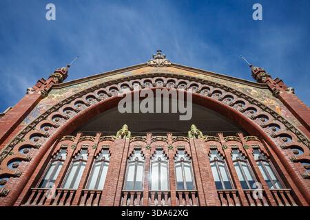 VALENCIA, SPANIEN - 6. APRIL 2025: Blick nach oben auf den kunstvollen Backsteinbogen und die Fenster des Mercat de Colom, Mercado de Colon in Valencia, einem ehemaligen Markt. Stockfoto