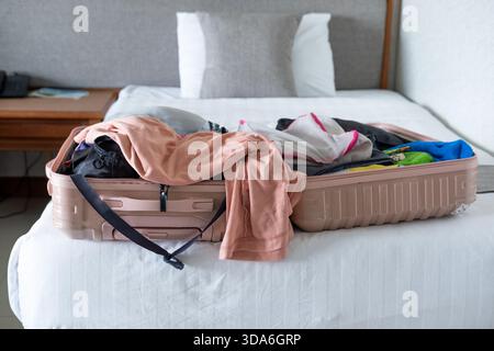 Der Reisende packt einen offenen Koffer auf dem Bett und organisiert alles, was er für eine kommende Reise braucht Stockfoto