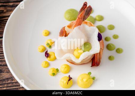 Elegantes Garnelengericht mit bunten Saucen und essbaren Blumen Stockfoto