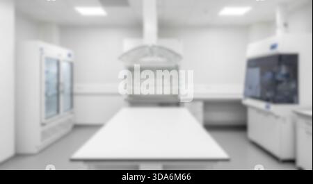 Verschwommenes, leeres, modernes wissenschaftliches Laborzimmer mit weißen Tischen, Kühlschränken und Abzugshaube für sterile Umgebungen oder chemische Forschung Stockfoto