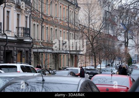 Autos füllen die Straße, während Fußgänger einen kalten Tag in der Stadt genießen. Podil, Kiew, Ukraine. Dezember 2025. Stockfoto