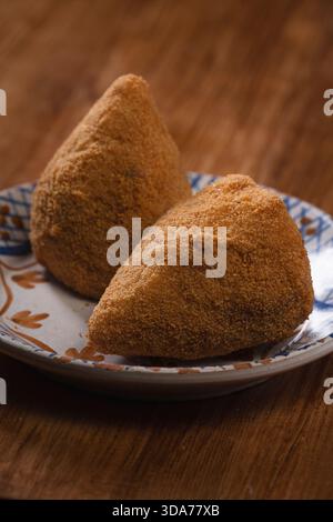 Zwei frisch gebratene sizilianische Arancini auf einem Servierteller. Blick aus einem hohen Winkel auf ein Duo traditioneller Reisbällchen, die gemeinsam genutzt werden können. Stockfoto