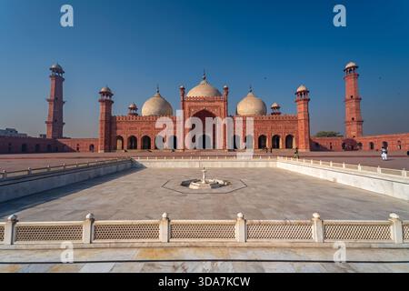 Blick auf die Pracht der Badshahi-Moschee mit ihrer roten Sandsteinfassade und den aufragenden Minaretten unter klarem Himmel in Lahore, Punjab, Pakistan. Stockfoto