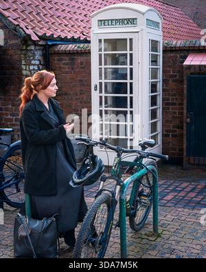 BEVERLEY, YORKSHIRE – 25. NOVEMBER: Attraktive Frau mit Handy und Telefonkiosk im Hintergrund am 25. November in Beverley, Großbritannien. Stockfoto
