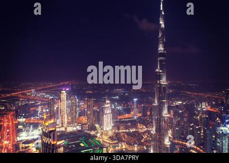 Atemberaubender nächtlicher Luftanblick auf den Burj Khalifa und die Skyline von Downtown Dubai mit beleuchteten Wolkenkratzern und pulsierenden Lichtern der Stadt in den VAE. Stockfoto