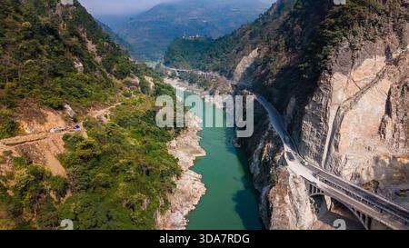 Aus der Vogelperspektive eines sich windenden Flusses, der sich durch zerklüftete Berge schlängelt, mit einer Straße, die sich an die Klippen schmiegt, einem Tanz der Natur und Infrastruktur, Pokhara, Stockfoto