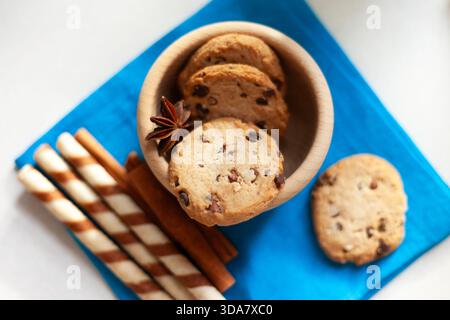 Schokoladenkekse in einer Holzschale mit Anis- und Waffelstäbchen und Zimt daneben, Blick von oben Stockfoto