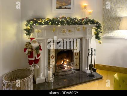 Ein traditioneller Kamin und Kaminsims, dekoriert für Weihnachten mit einer Girlande und Feenlichtern in einem Wohnzimmer Stockfoto